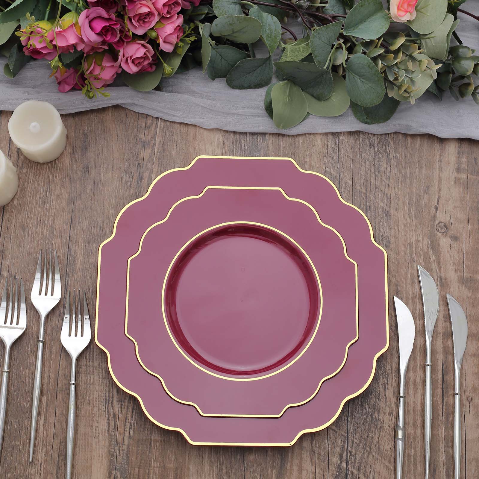 Burgundy hard plastic Baroque dinner plate with gold rim on a wooden table.