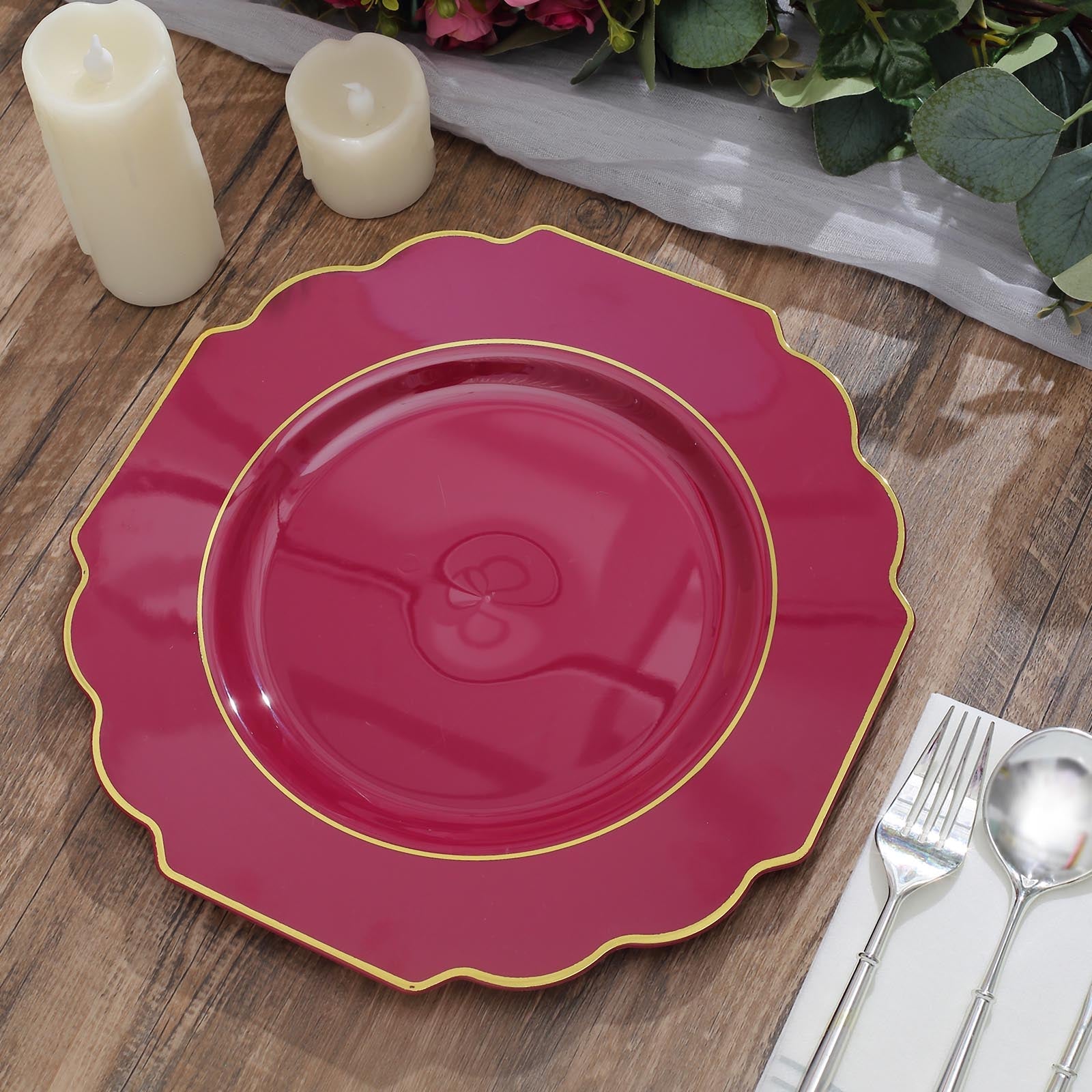 Burgundy hard plastic Baroque dinner plate with gold rim on a wooden table.
