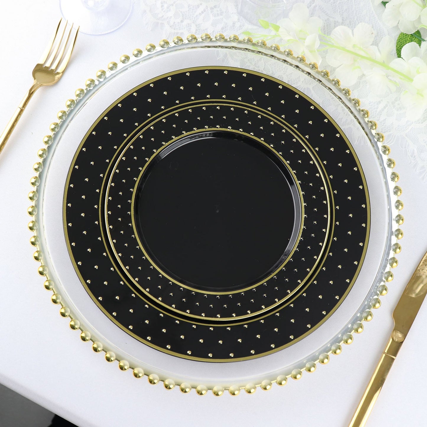 Black and gold 3D round plastic appetizer plates with polka dotted rim.