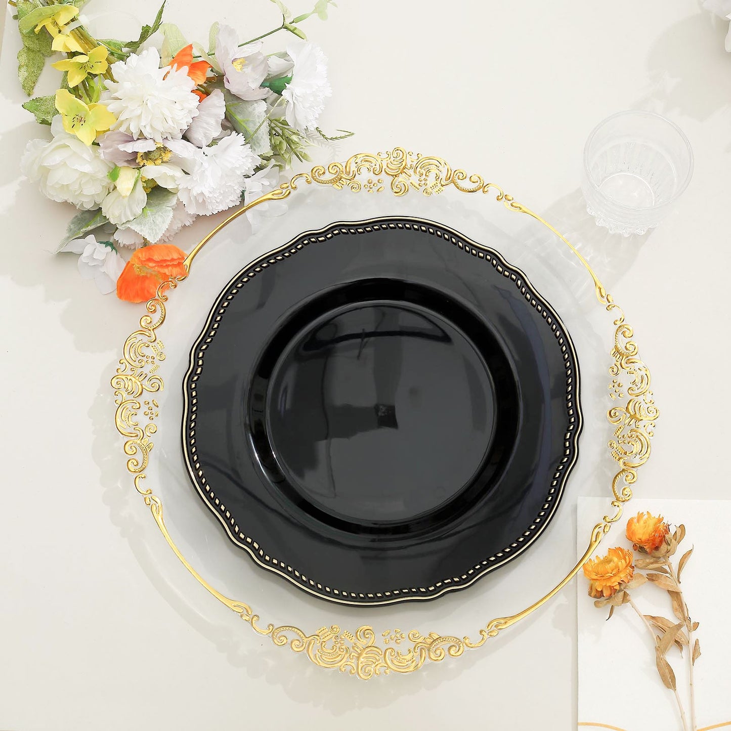 Elegant black plate on a gold charger with floral decor for a stylish table setting.