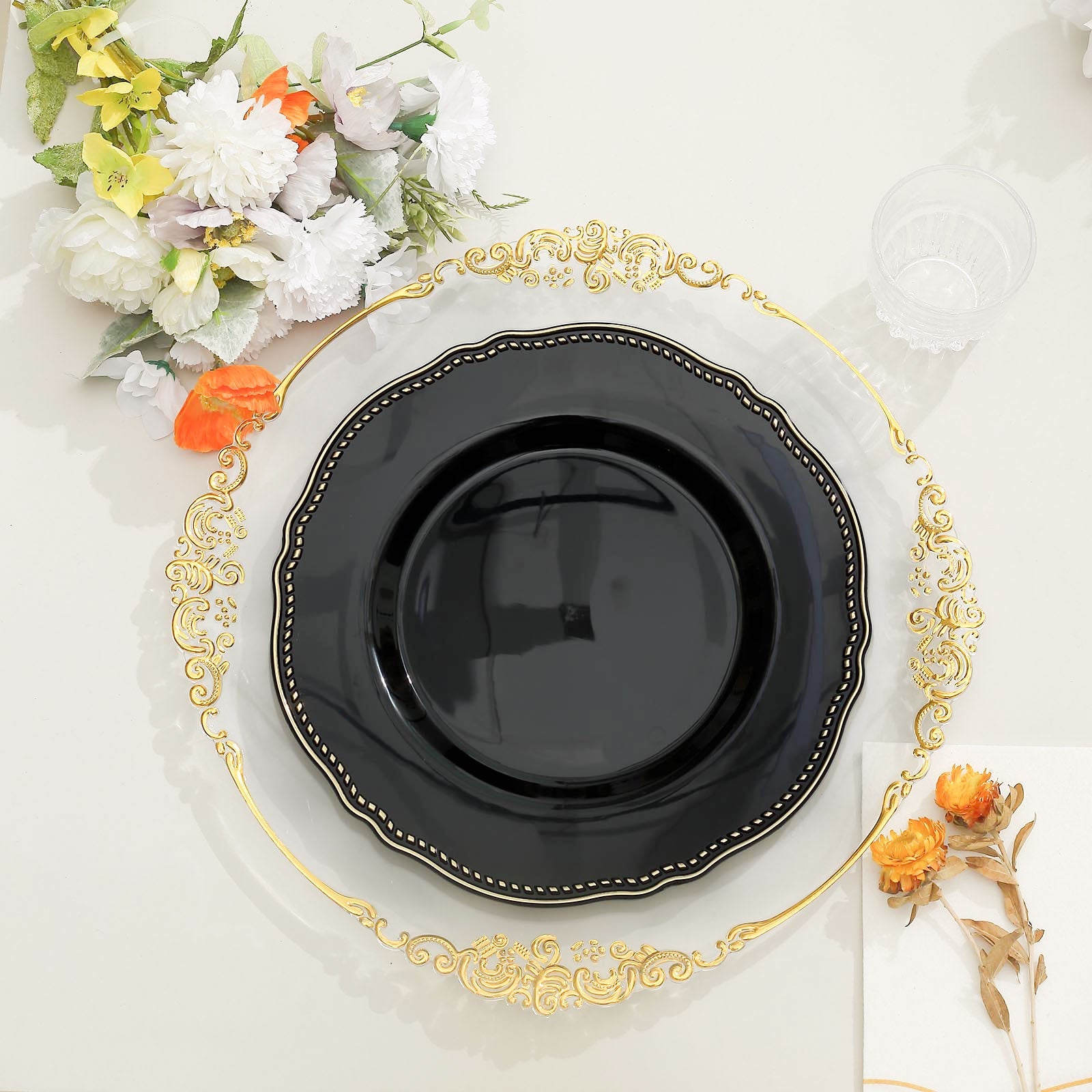 Elegant black plate on a gold charger with floral decor for a stylish table setting.