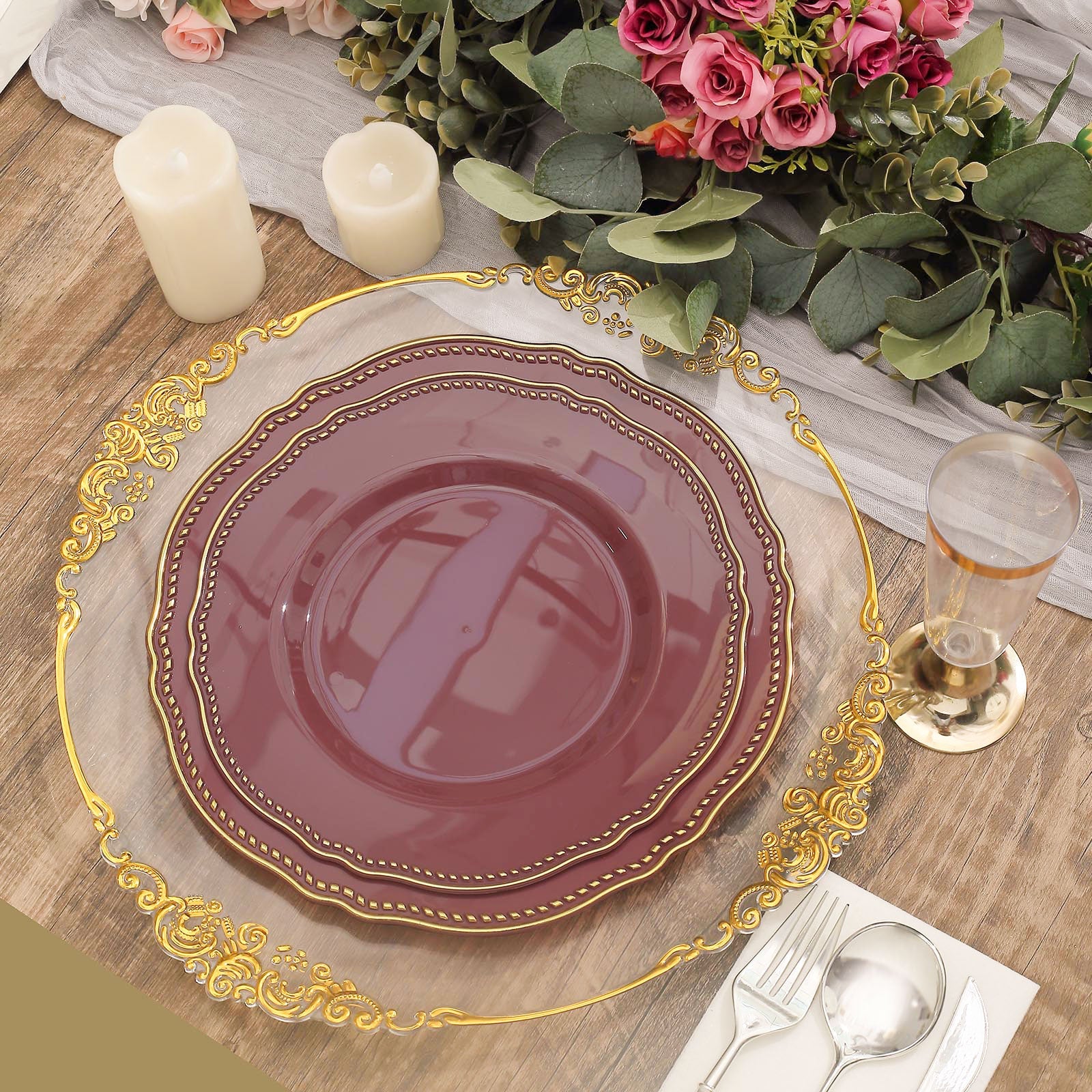 Elegant table setting with burgundy plates, gold accents, candles, and floral arrangements.
