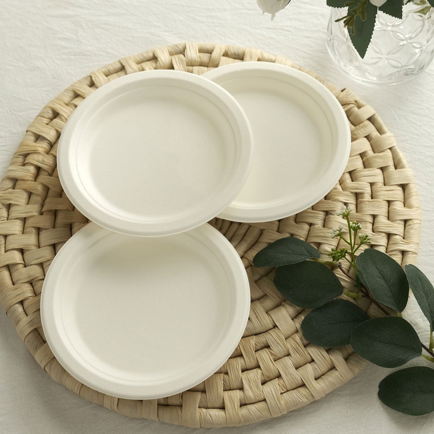 White biodegradable bagasse dessert plates on a woven placemat.