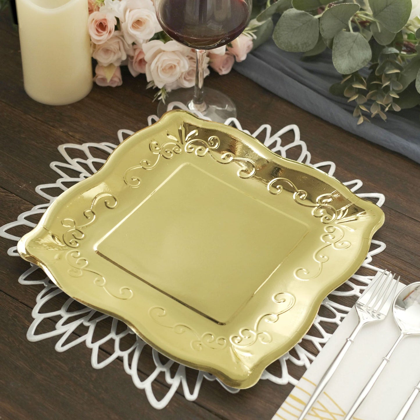 Gold vintage square dinner plate with embossed scroll design on a table setting.