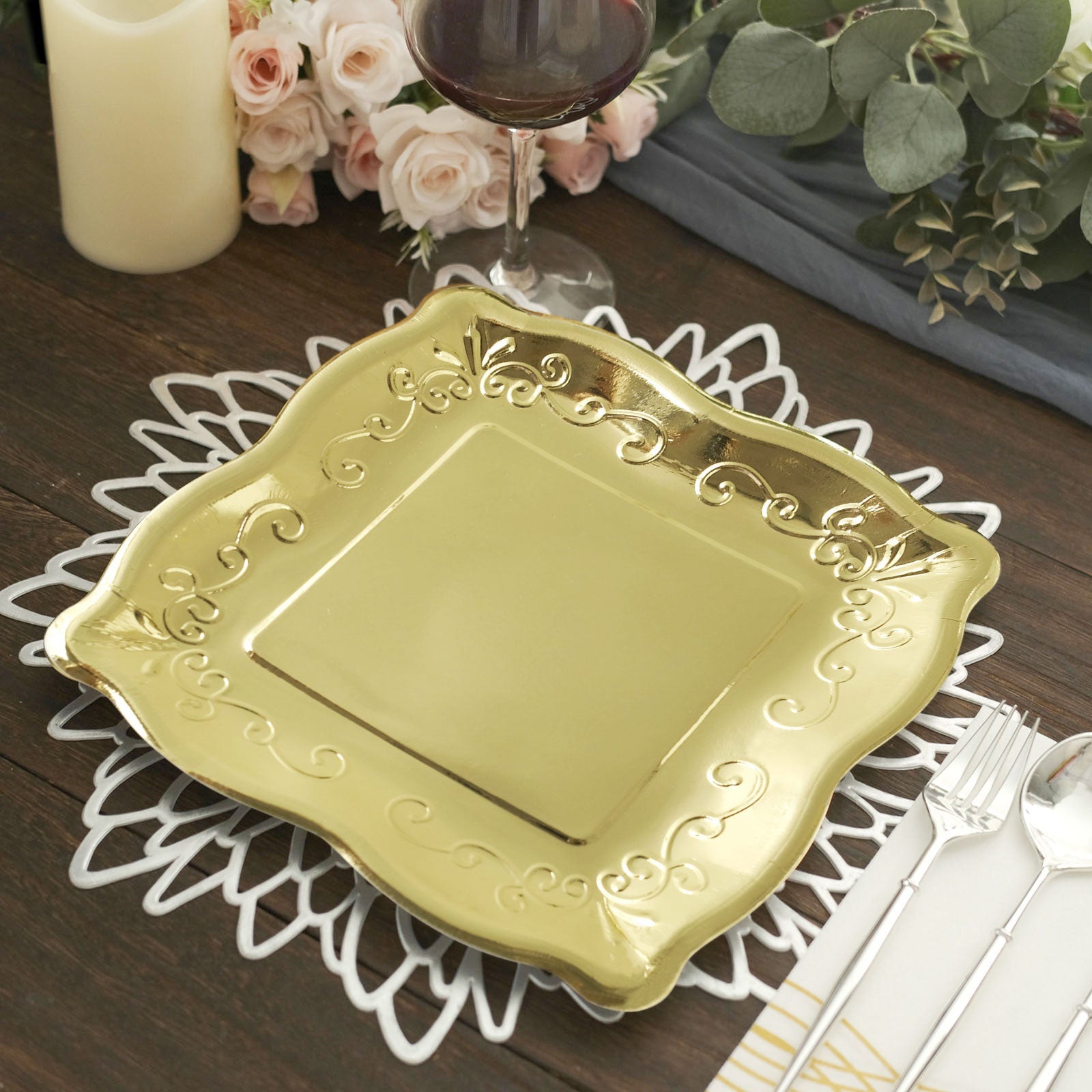 Gold vintage square dinner plate with embossed scroll design on a table setting.