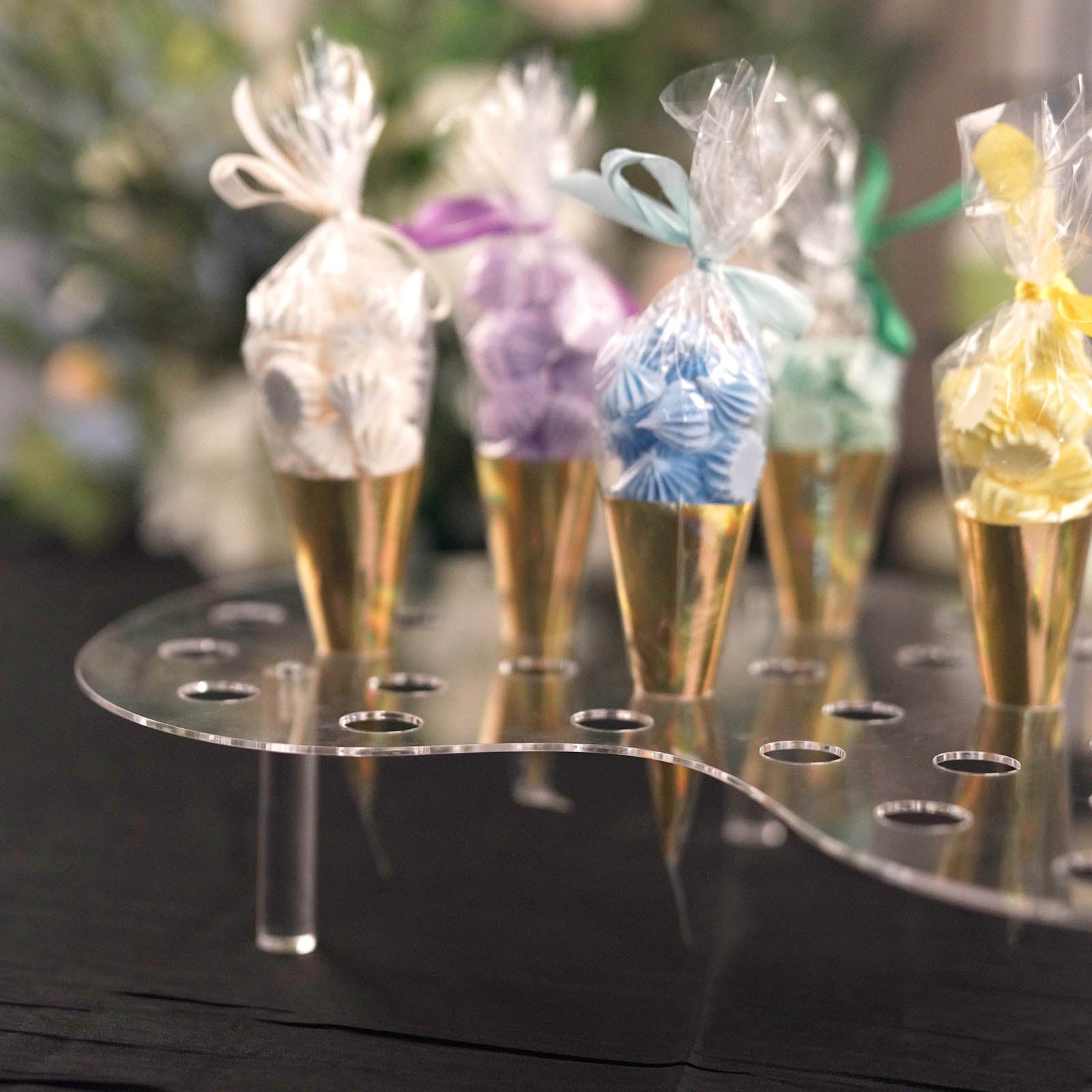 Clear acrylic ice cream cone display stand with colorful mini snow cones.