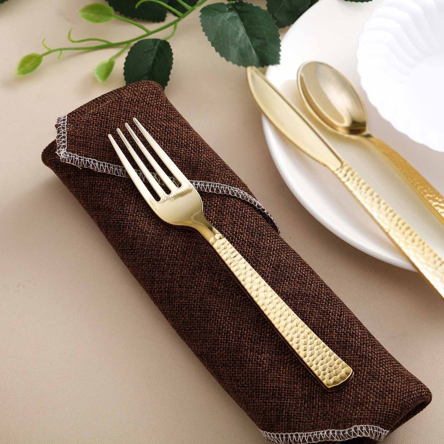 Gold hammered style plastic fork on a brown napkin.