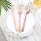 Rose gold hammered plastic forks on a decorative plate.