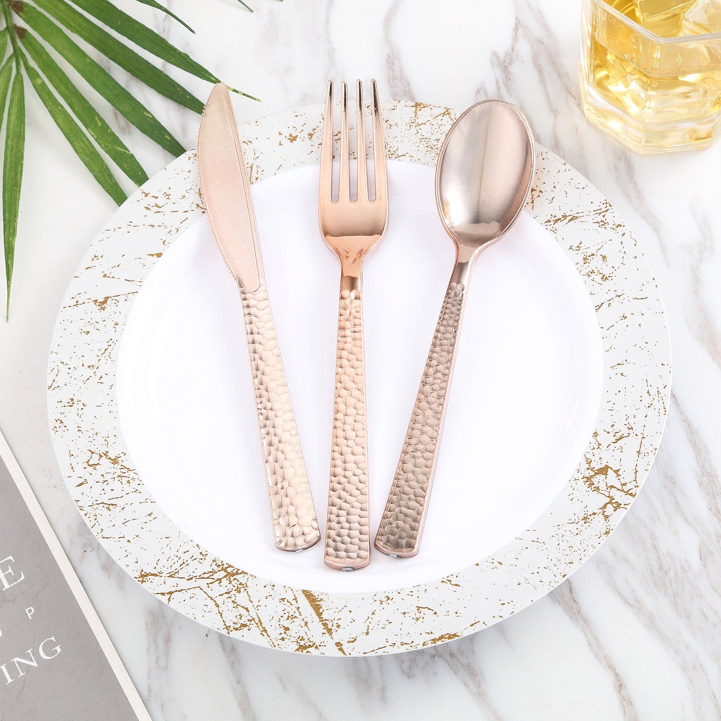 Rose gold hammered plastic forks on a decorative plate.