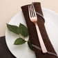 Rose gold hammered plastic fork on a napkin and plate.