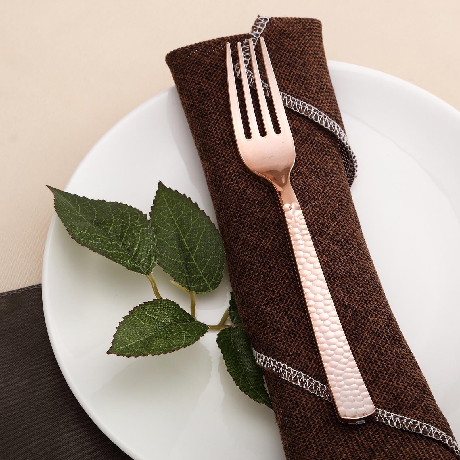 Rose gold hammered plastic fork on a napkin and plate.