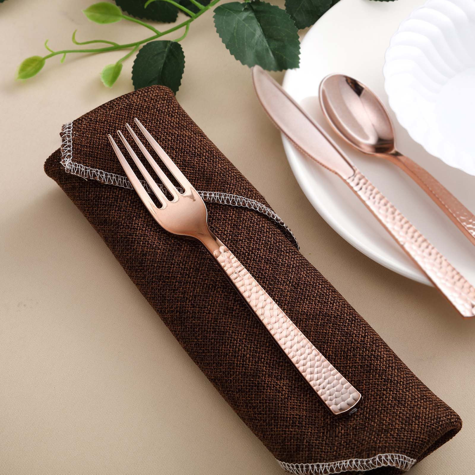 24 Pack rose gold hammered style heavy duty plastic forks on a brown napkin.