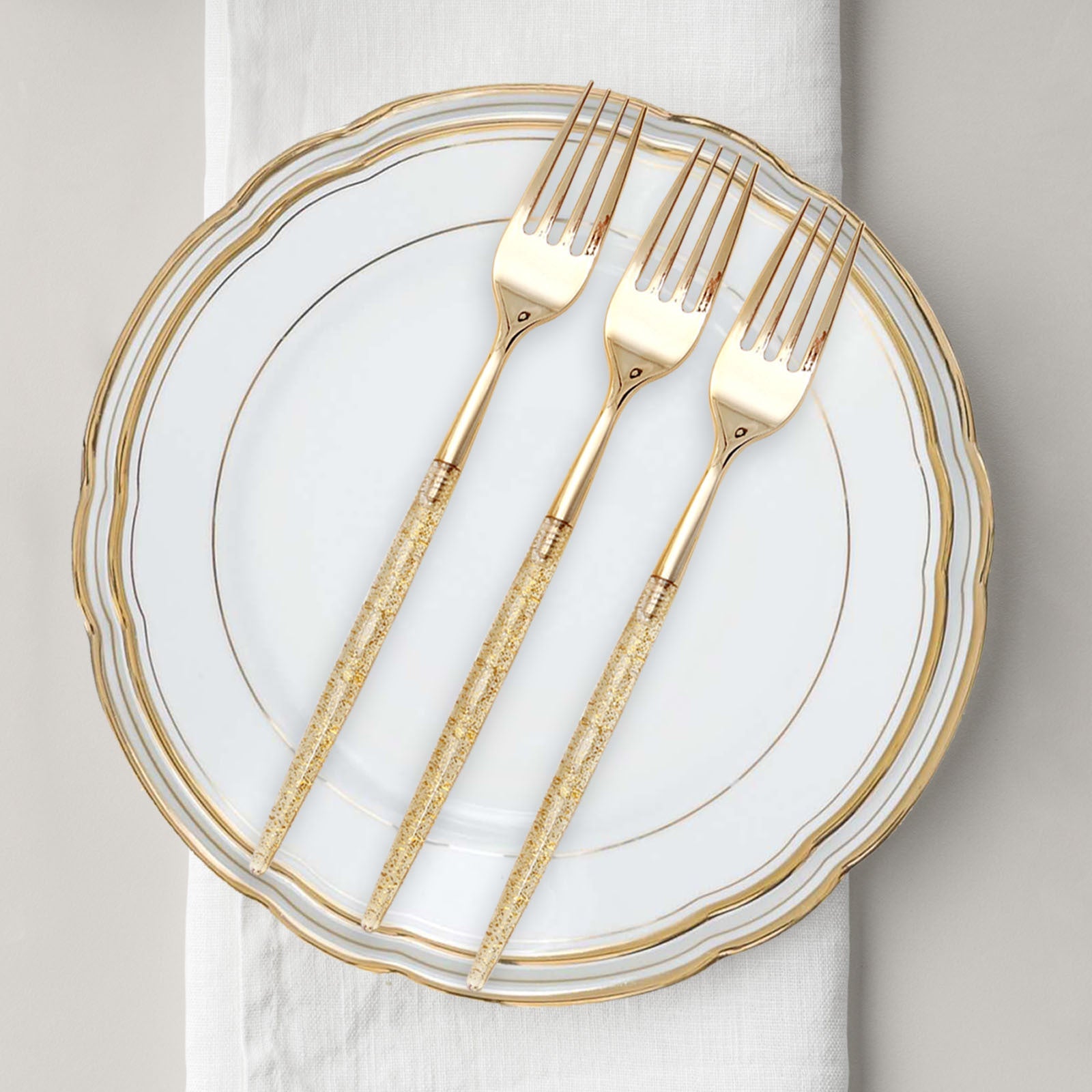Gold glittered disposable forks on a decorative plate.