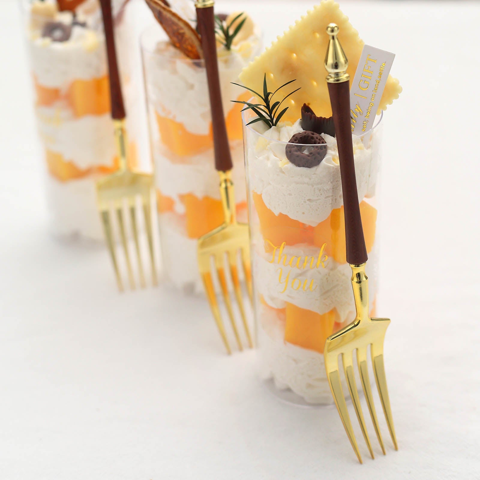 Gold plastic dessert forks with Roman column handle in a dessert display.