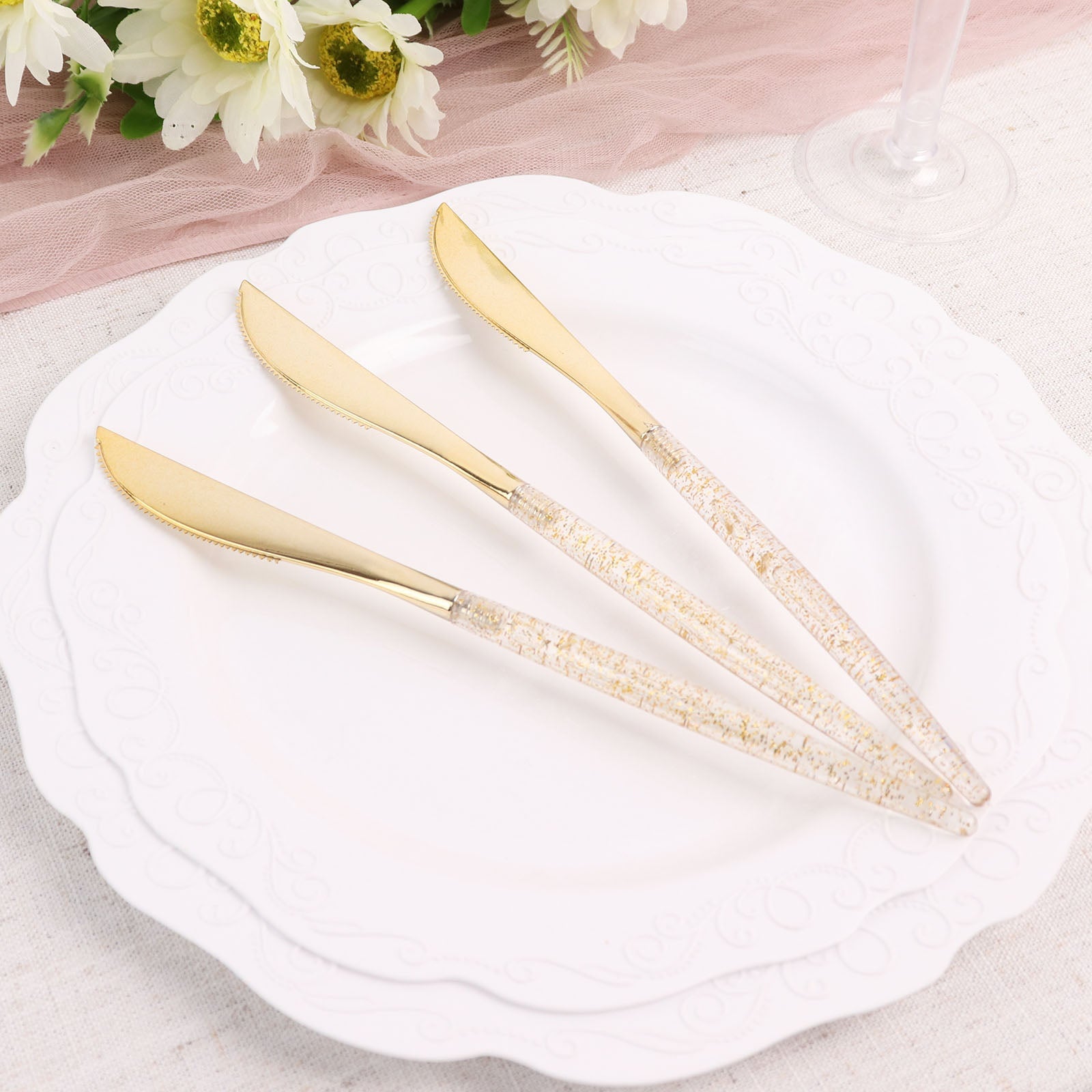 Gold glittered disposable knives on a plate.