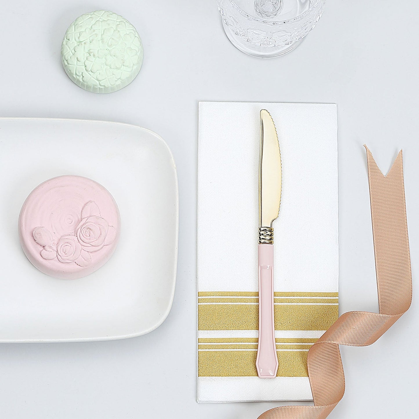 Gold 7.5" heavy duty plastic knife with blush handle on a white napkin.