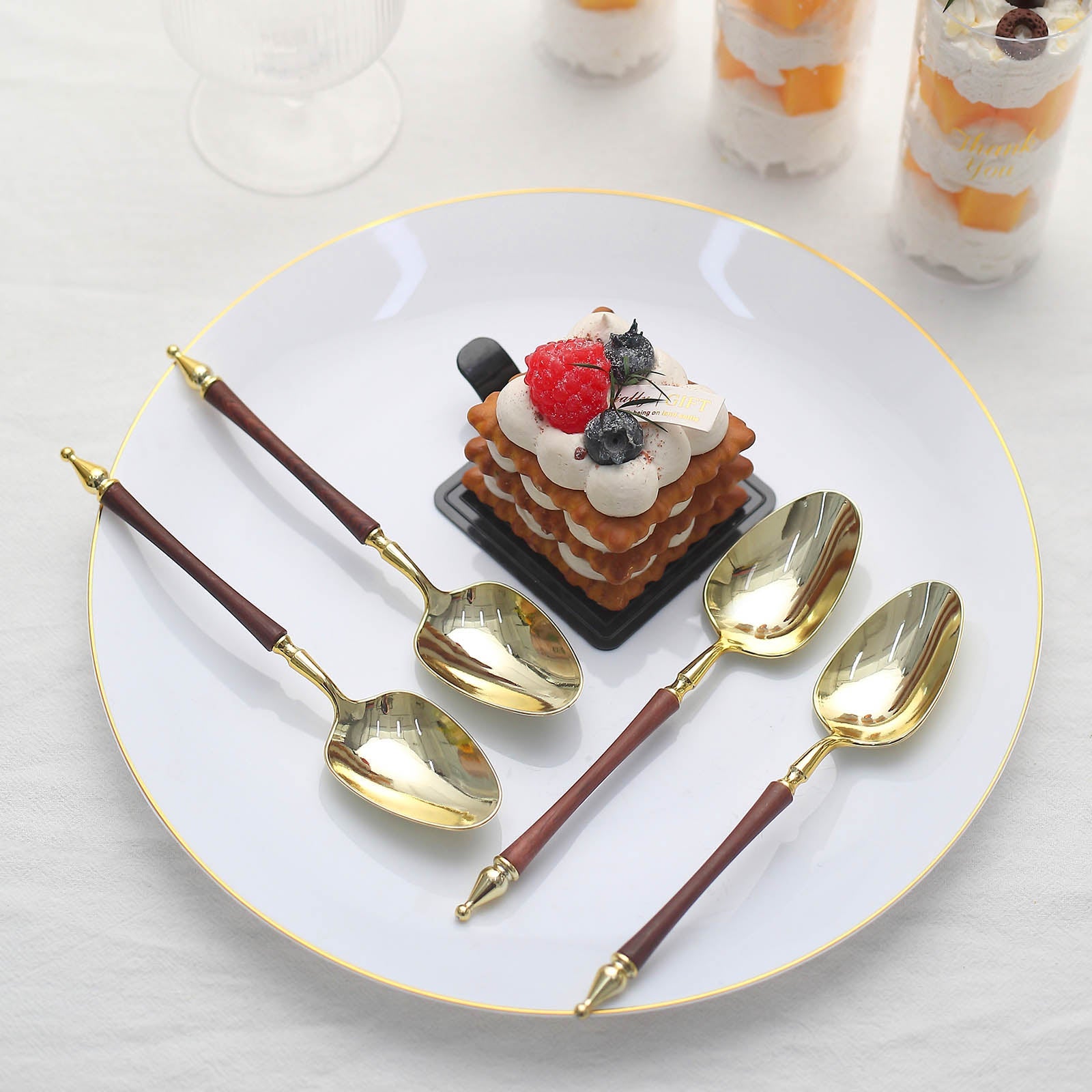 Gold and brown disposable dessert spoons on a plate with dessert.