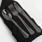 Clear plastic cutlery set on a black napkin for elegant dining.
