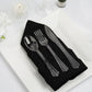 Elegant black napkin with clear plastic cutlery on a white plate. Perfect for dining settings.