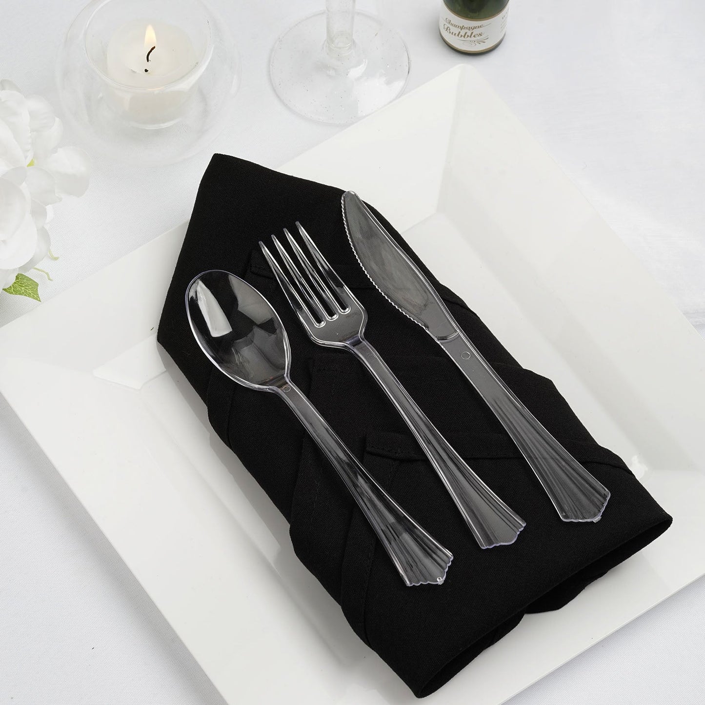 Elegant black napkin with clear plastic cutlery on a white plate. Perfect for dining settings.