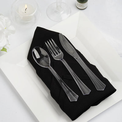 Elegant black napkin with clear plastic cutlery on a white plate. Perfect for dining settings.