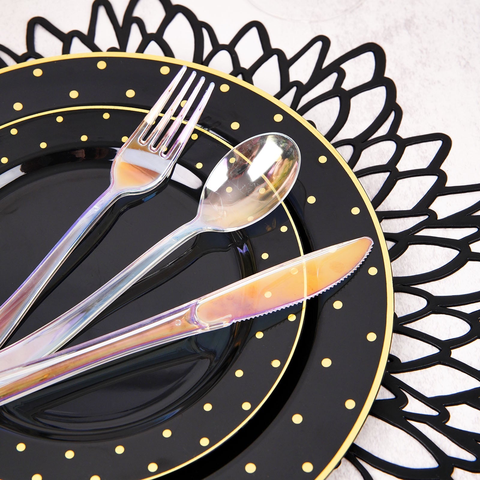 Iridescent disposable cutlery set on black plates with gold accents.