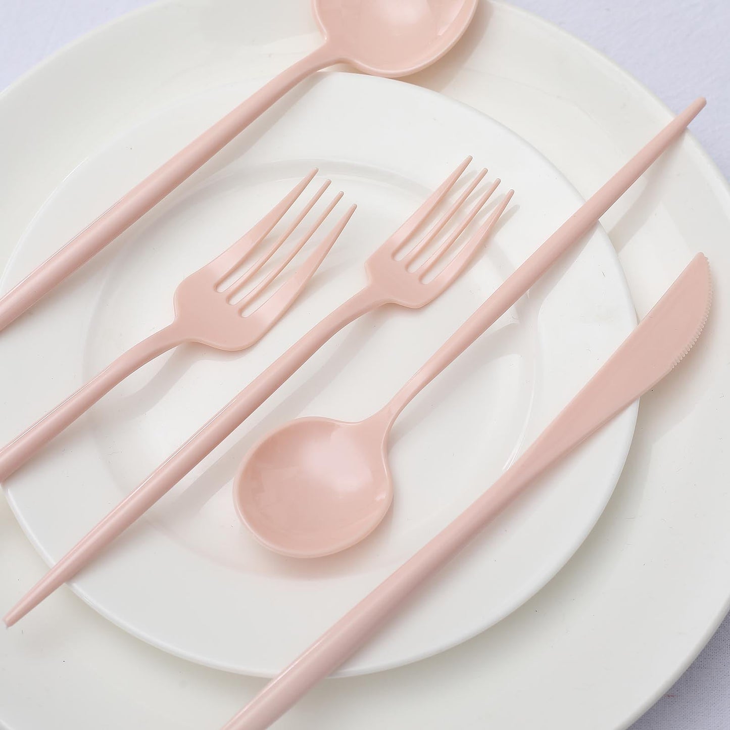Blush pink heavy duty plastic utensil set on a white plate.
