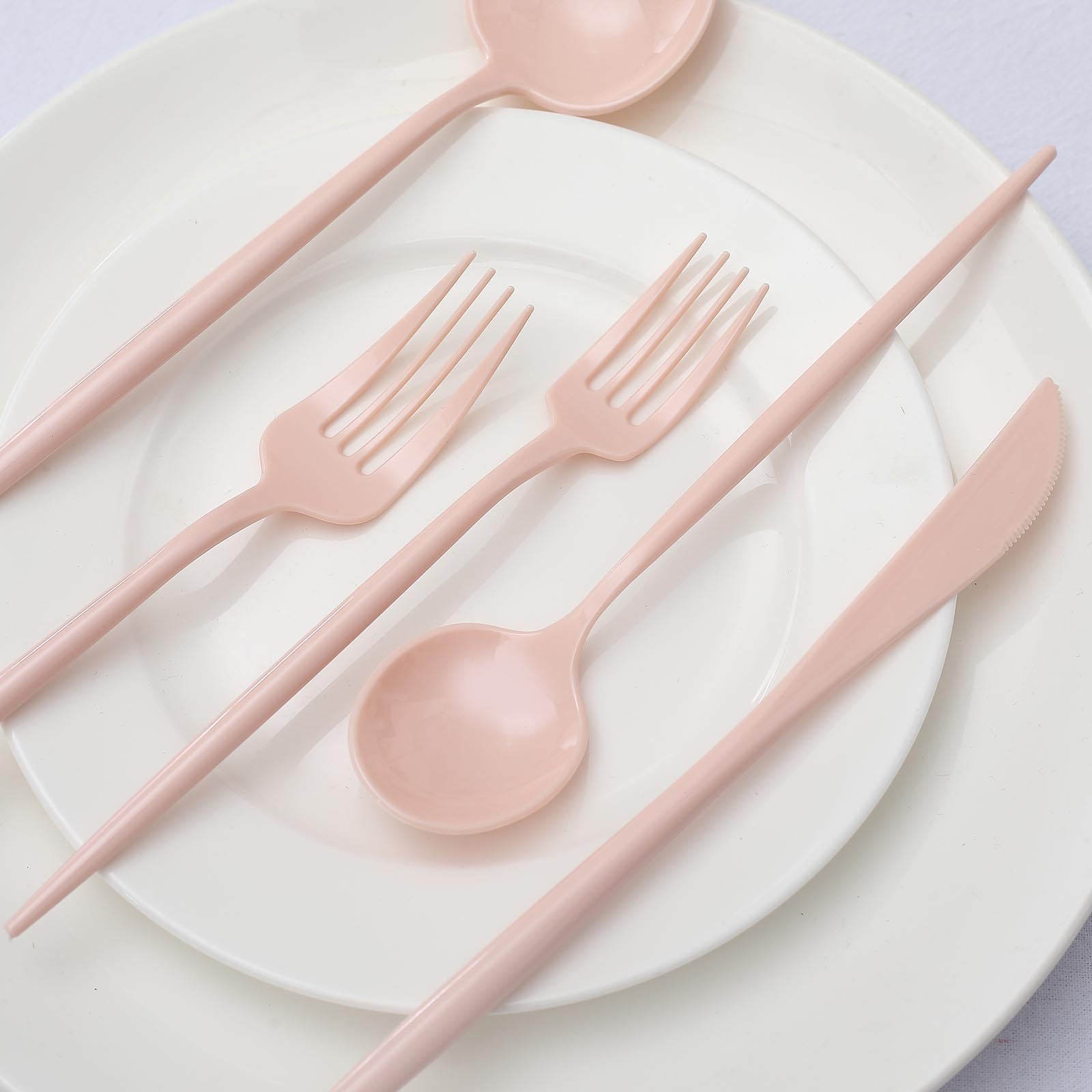 Blush pink heavy duty plastic utensil set on a white plate.