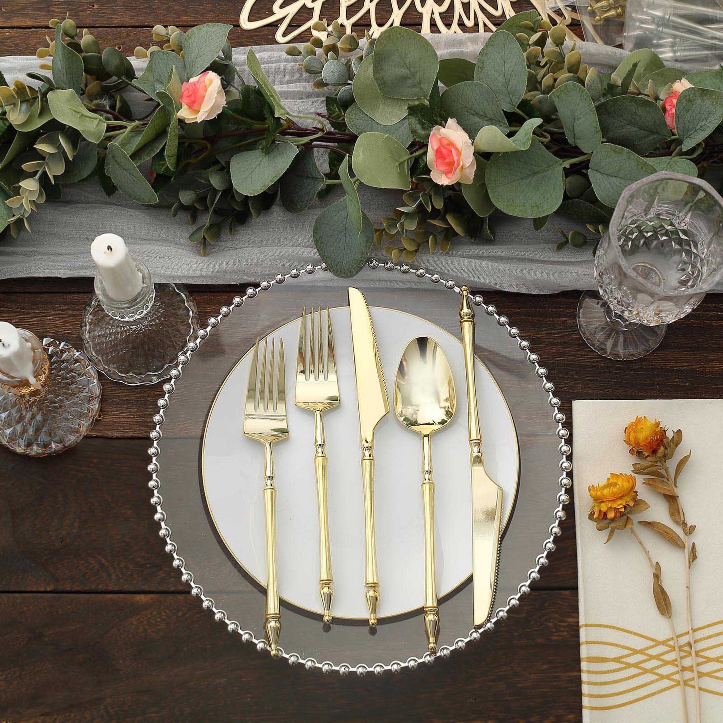 Gold disposable utensil set with Roman column handle on a decorative plate.