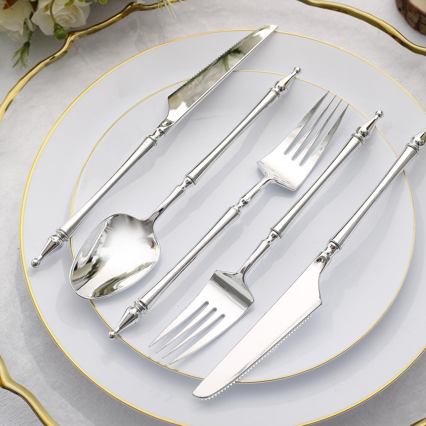 Silver disposable utensil set with Roman column handle on a plate.