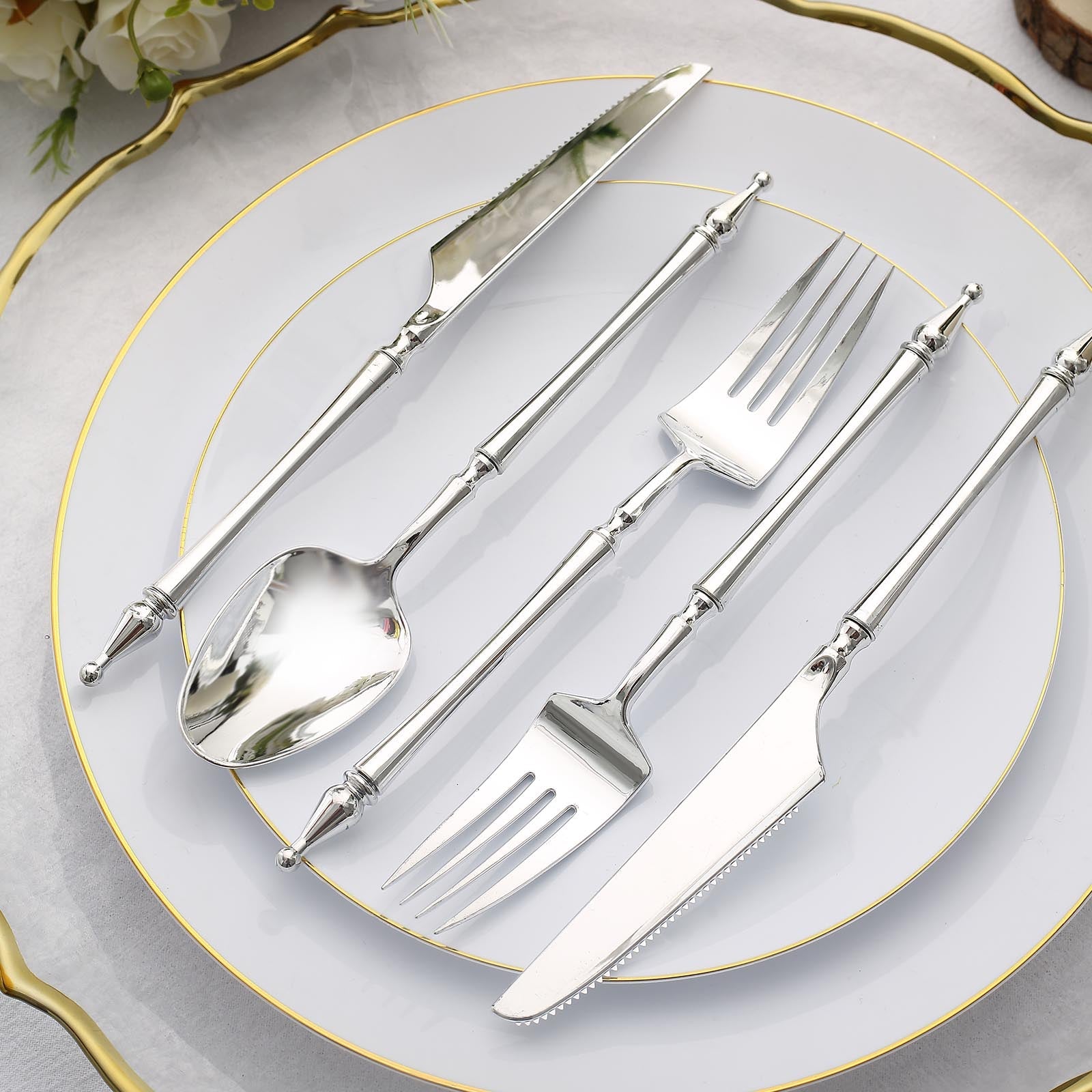 Silver disposable utensil set with Roman column handle on a plate.