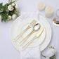 Gold disposable utensils set on a white plate with a floral arrangement.