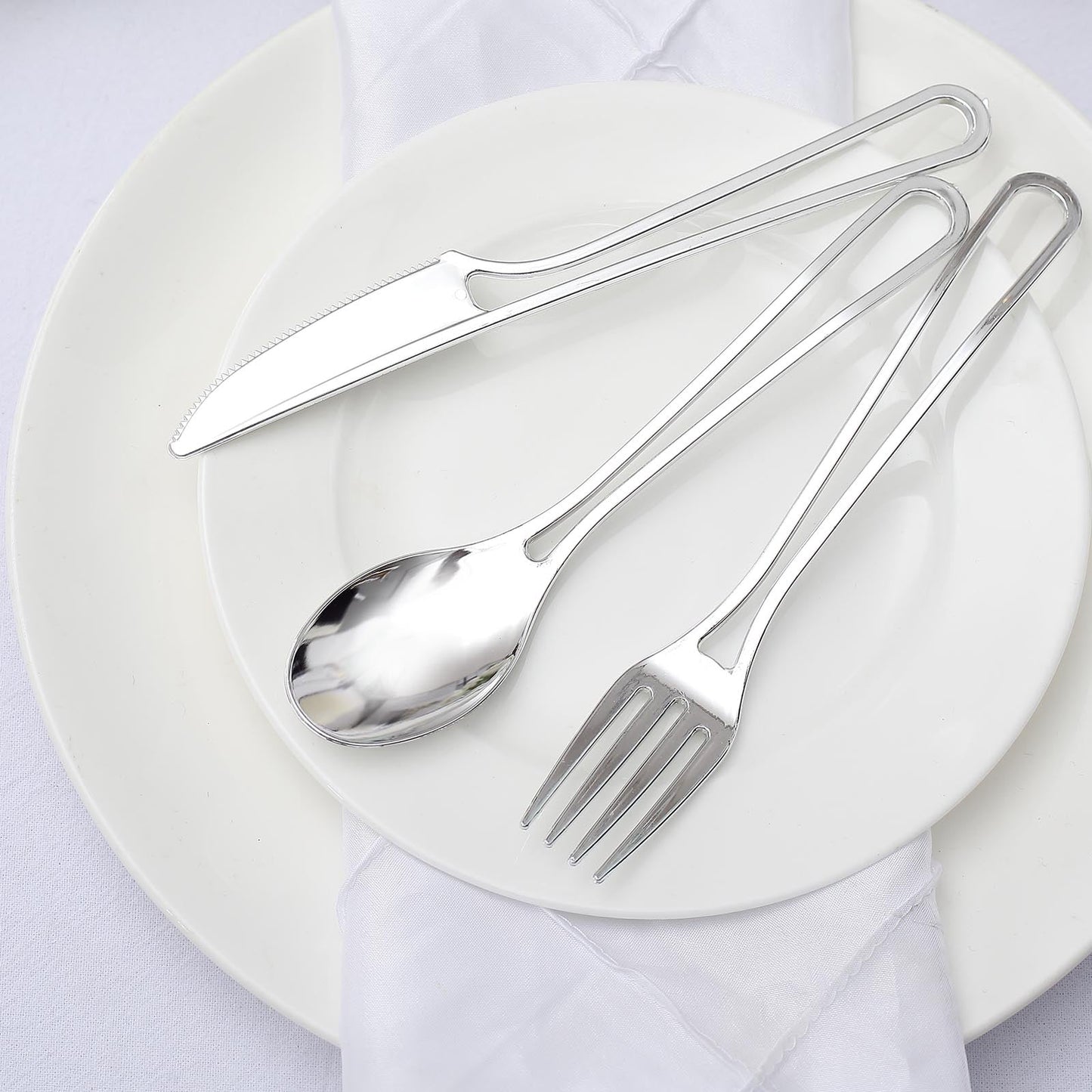 Silver disposable utensils set on a white plate.