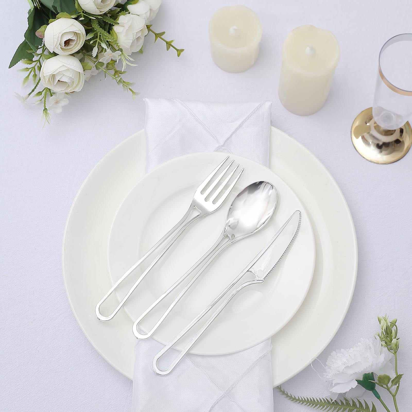 24 Pack silver plastic utensil set on a white table setting.