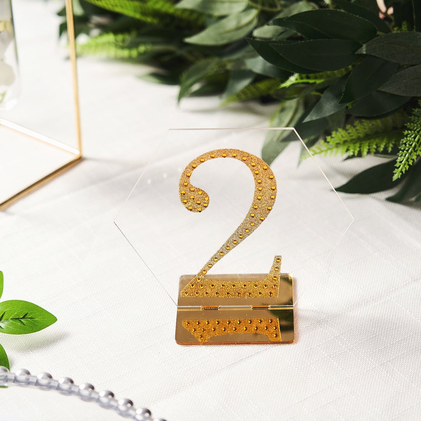 Clear and gold acrylic hexagon table sign holder with number two.