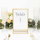 Gold frame acrylic table sign holder displaying "Table 1" with floral decor.