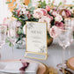 Gold freestanding table sign holder displaying a menu among pink flowers.