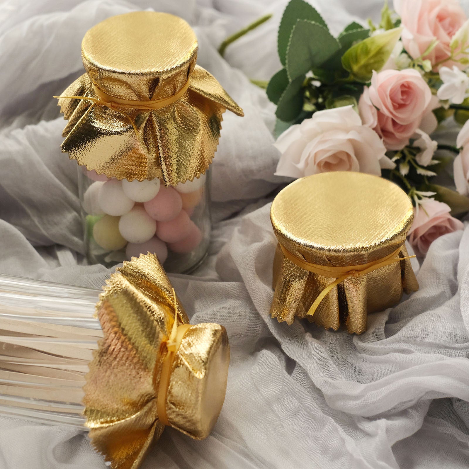 Metallic gold round party favor jar covers with satin ties.
