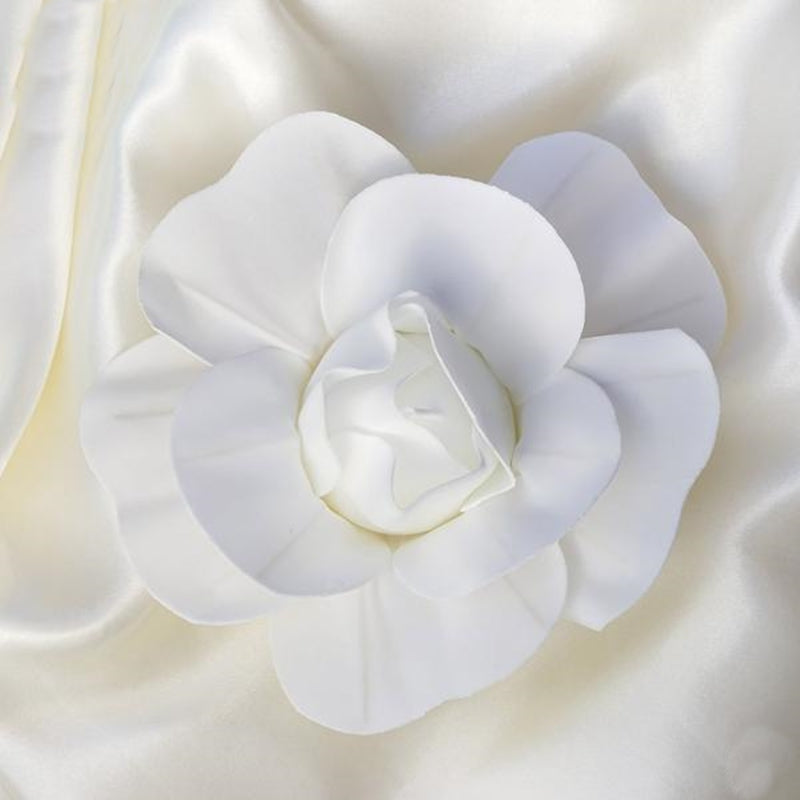 White real touch artificial foam rose on satin fabric.