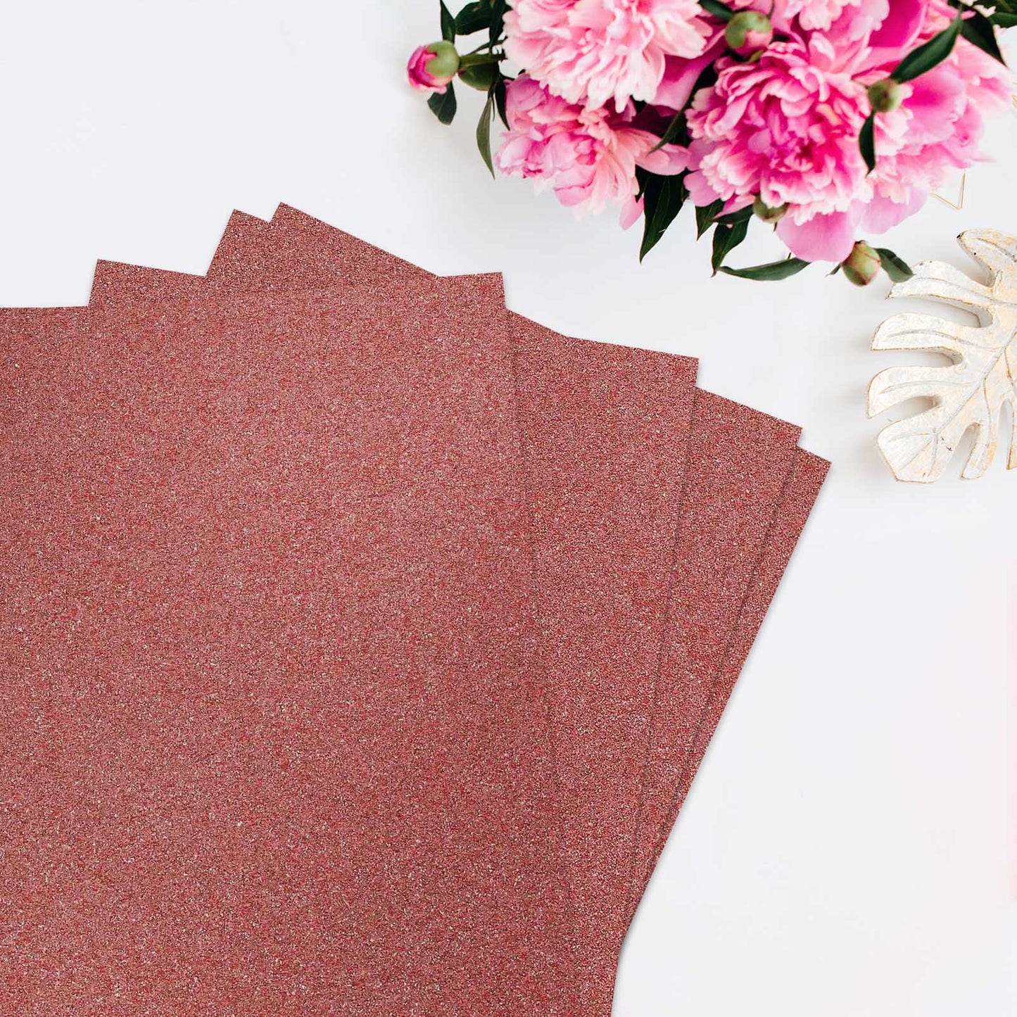 Rose gold self-adhesive glitter craft foam sheets stacked on a white surface.