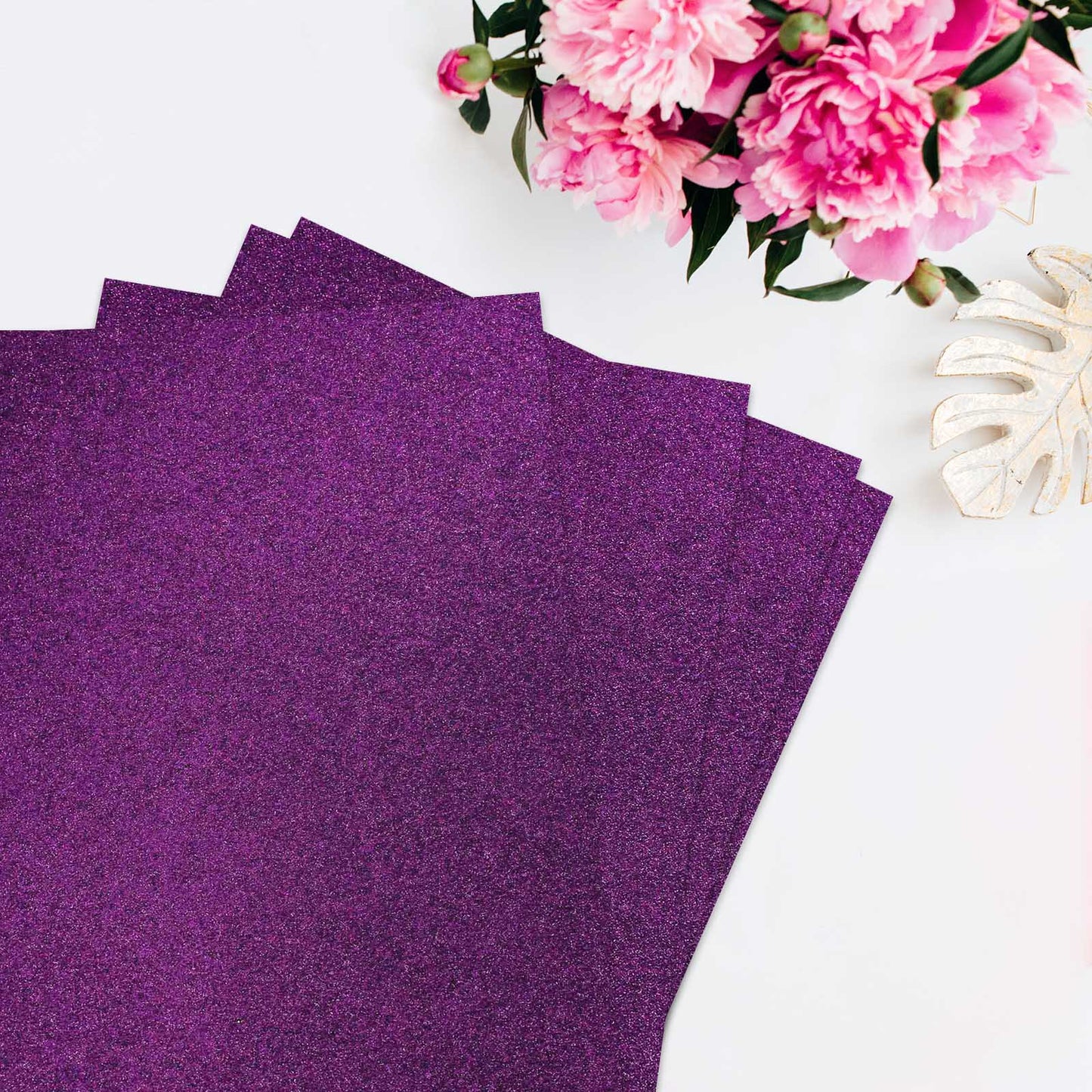 Purple self-adhesive glitter craft foam sheets arranged with flowers.