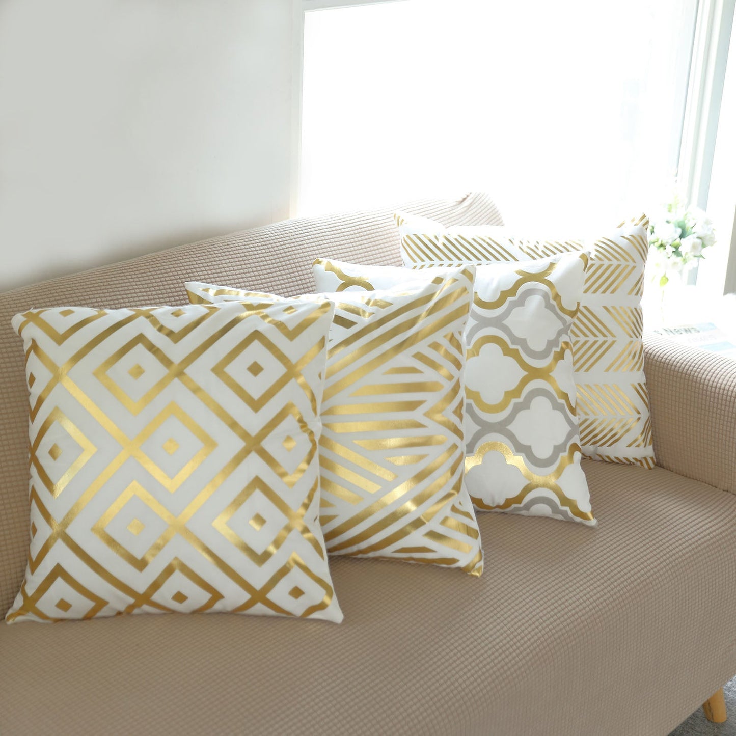 18" white and gold foil geometric print throw pillow covers on a sofa.