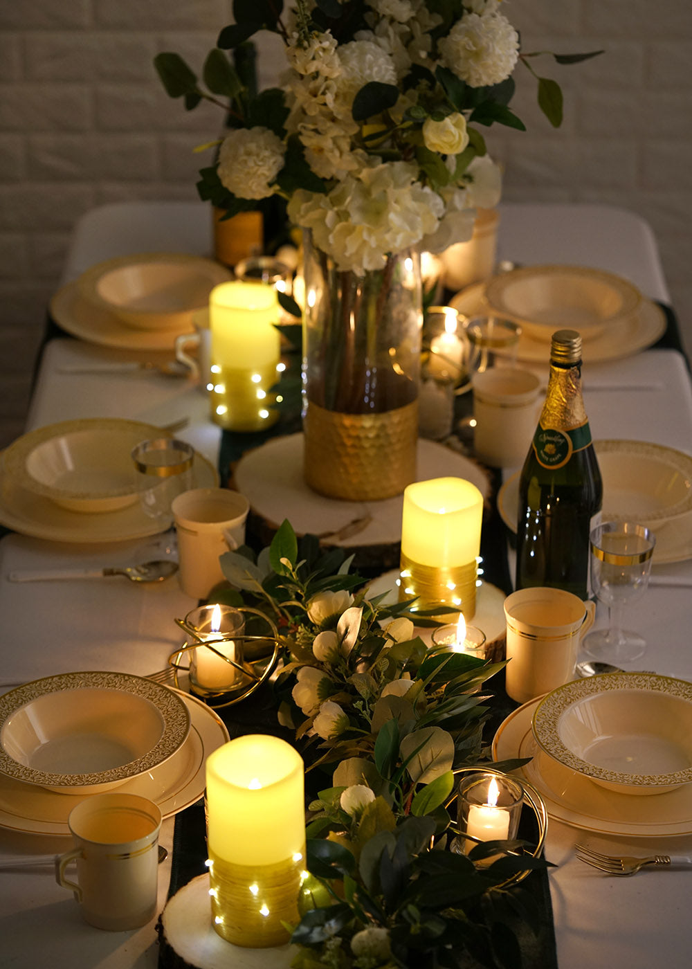 Set of 3 gold LED pillar candles with fairy lights on a beautifully arranged table.
