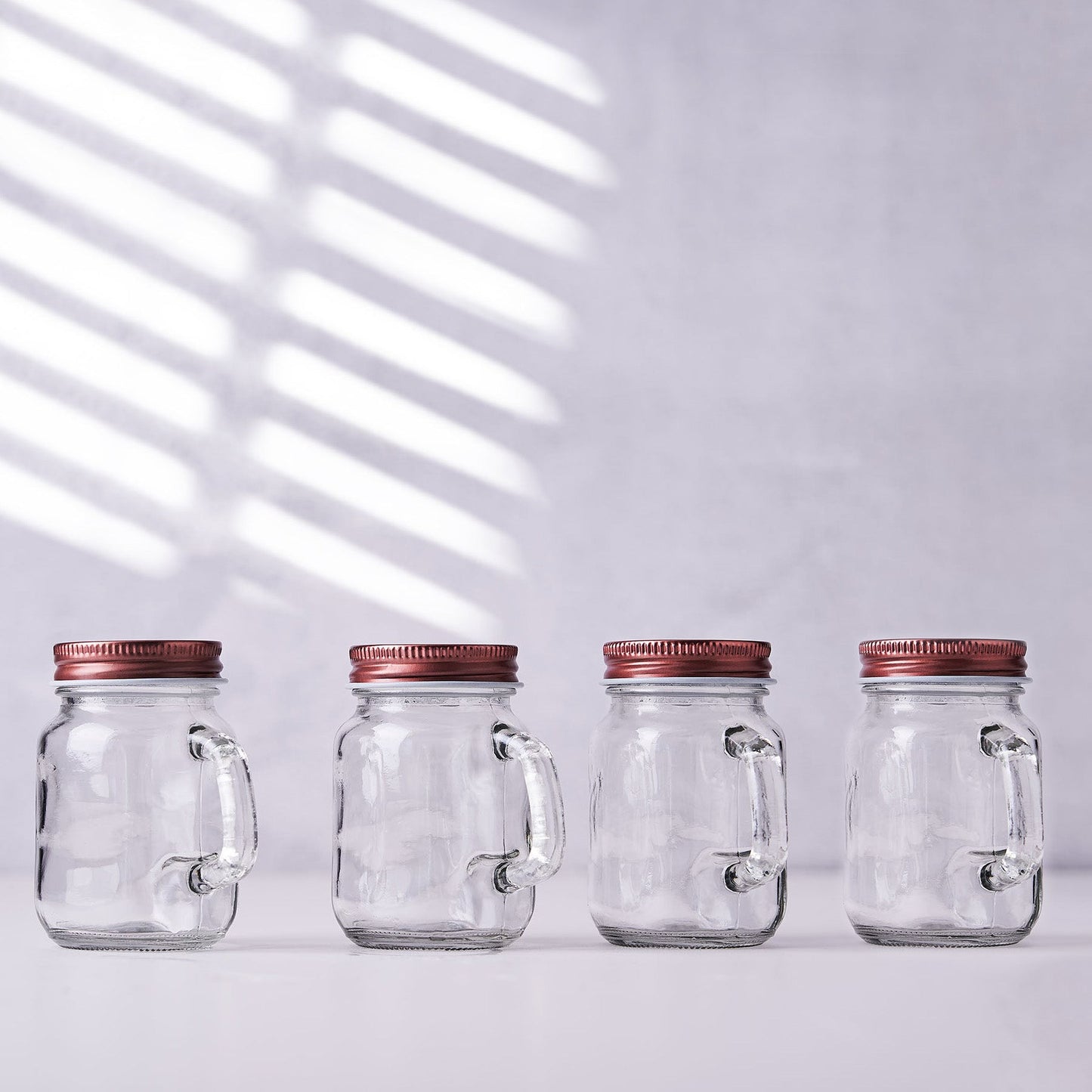 Rustic clear glass mason jars with rose gold lids.