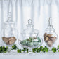 Clear glass pedestal apothecary jars with lids, perfect for party favors.