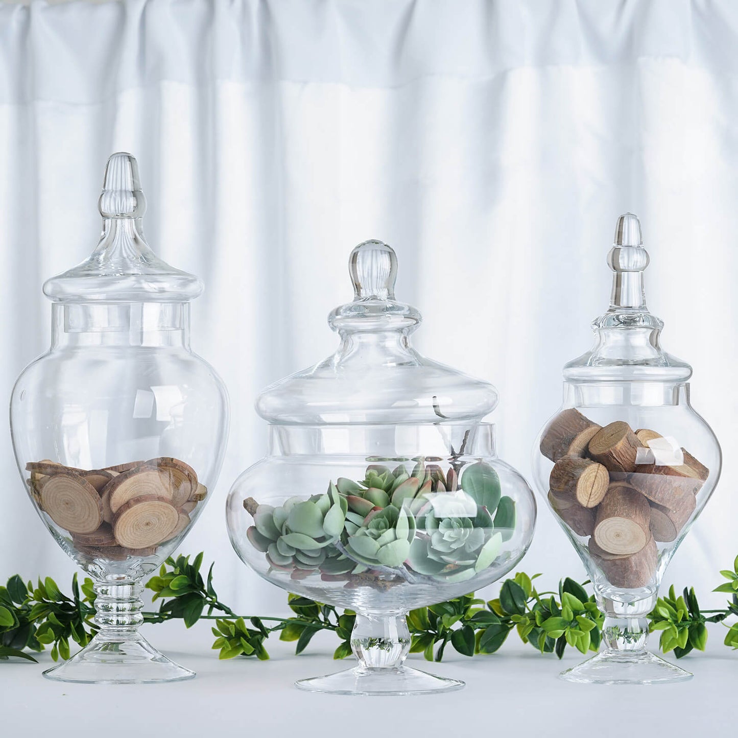 Clear glass pedestal apothecary jars with lids, perfect for party favors.