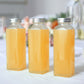 Clear glass jars with aluminum caps filled with orange liquid.
