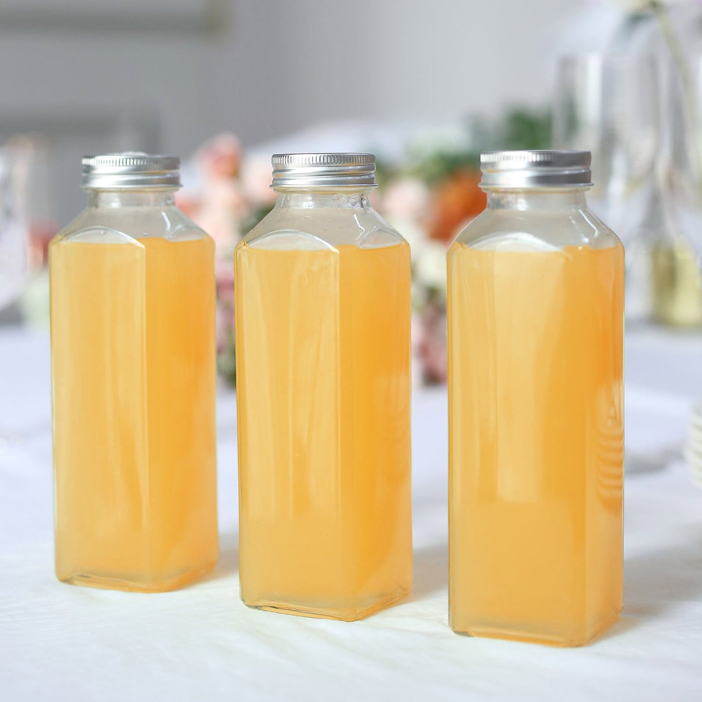 Clear glass jars with aluminum caps filled with orange liquid.