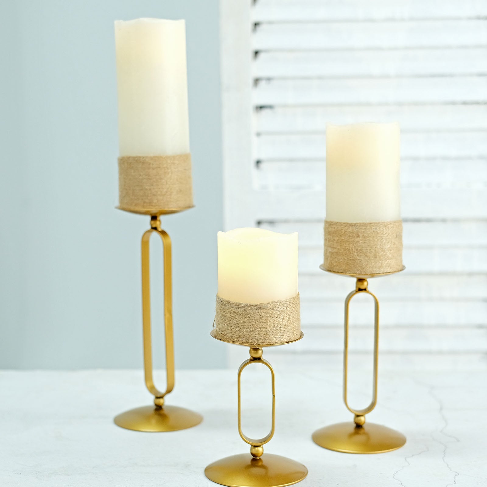 Gold metal oval frame candle holders in assorted sizes with pillar candles.