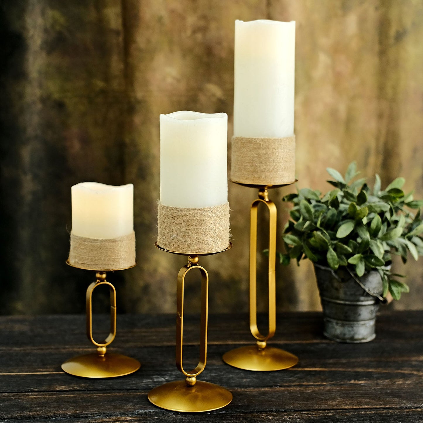 Gold metal oval frame pillar candle holders with white candles, assorted sizes.